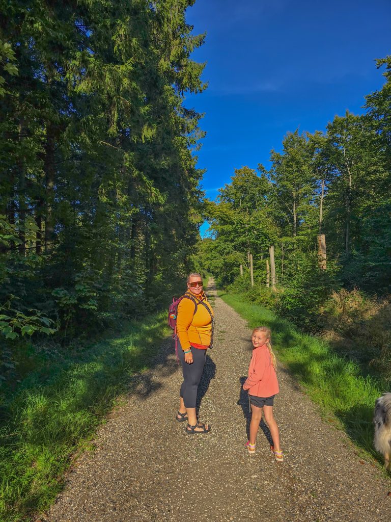 Mother and daughter hiking together on a sunny forest trail in Denmark.
