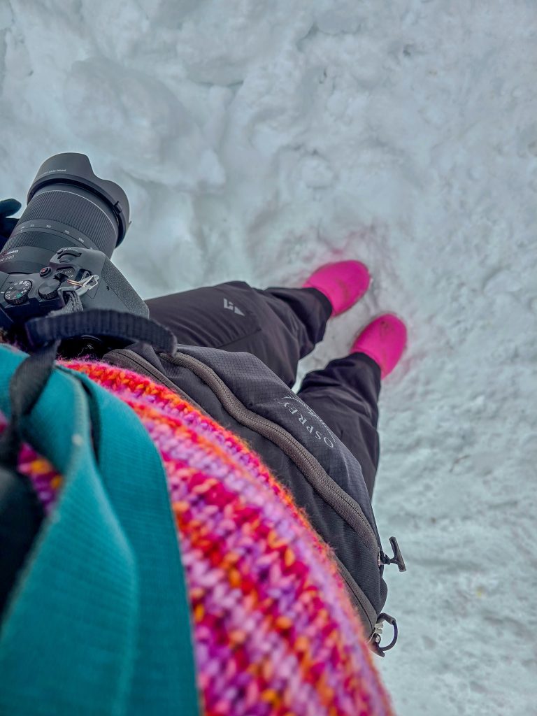 Outdoor photographer carrying a camera while exploring a snowy winter landscape.