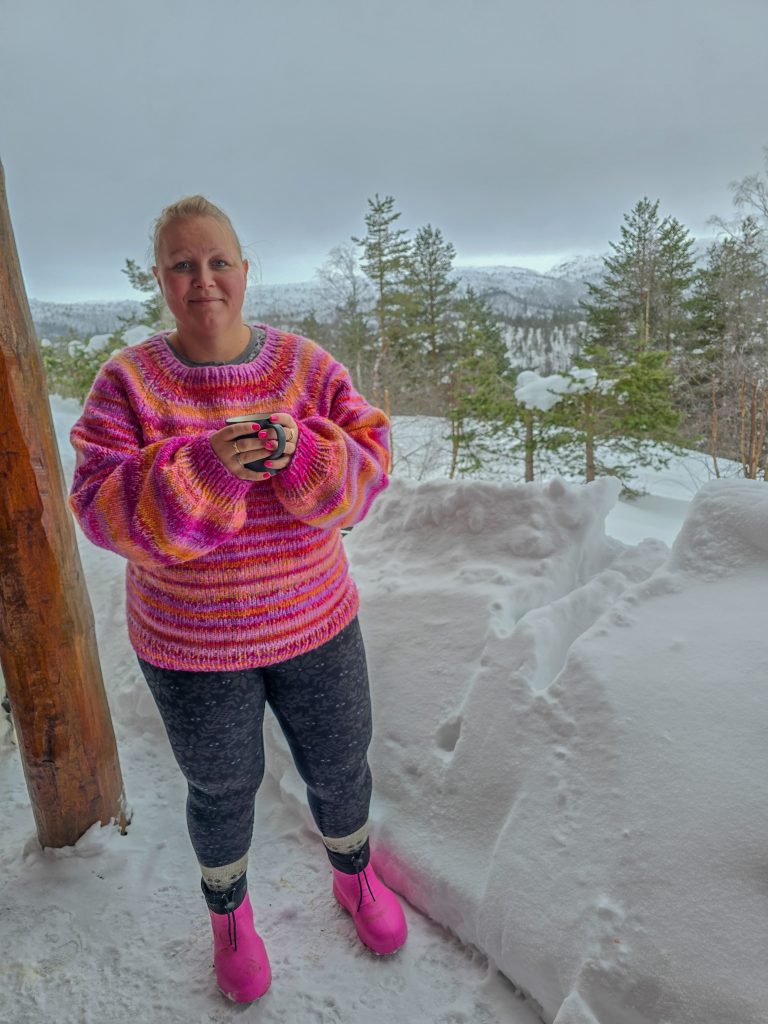 Woman enjoying a winter day in the snowy mountains, wearing colourful outdoor clothing.