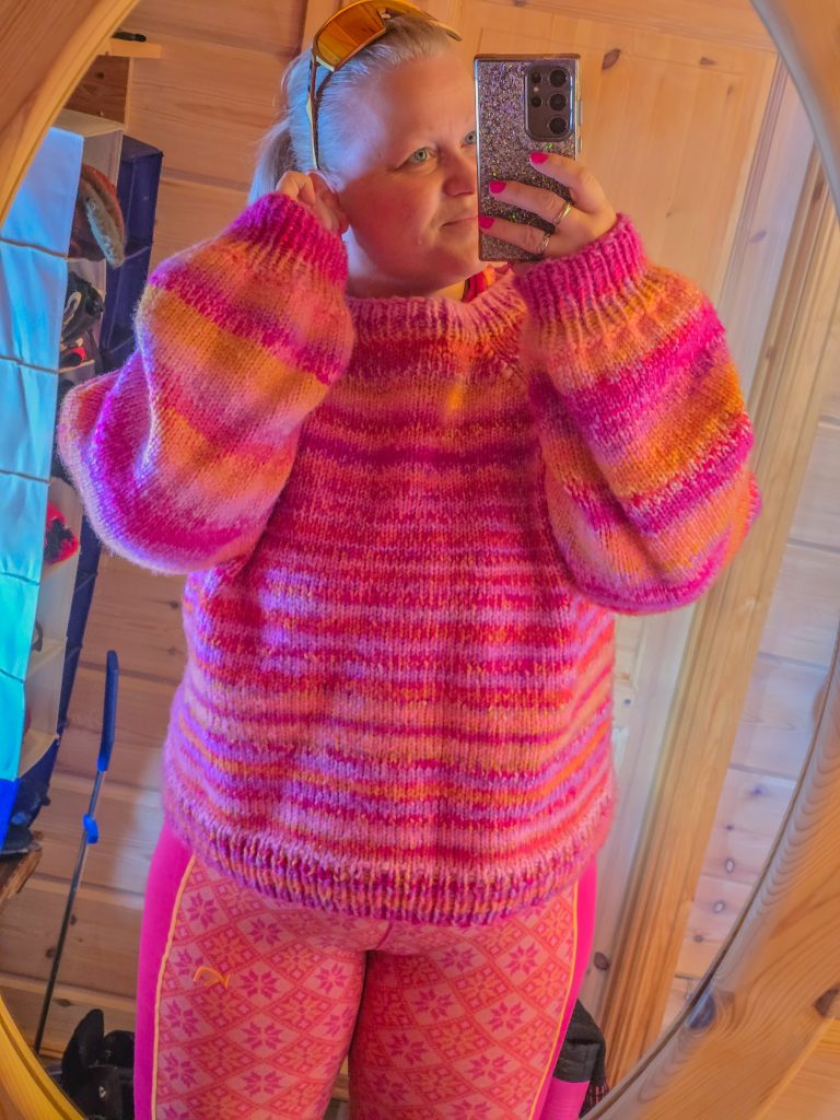 Woman wearing a colourful pink and orange knitted sweater with patterned outdoor base layer leggings.