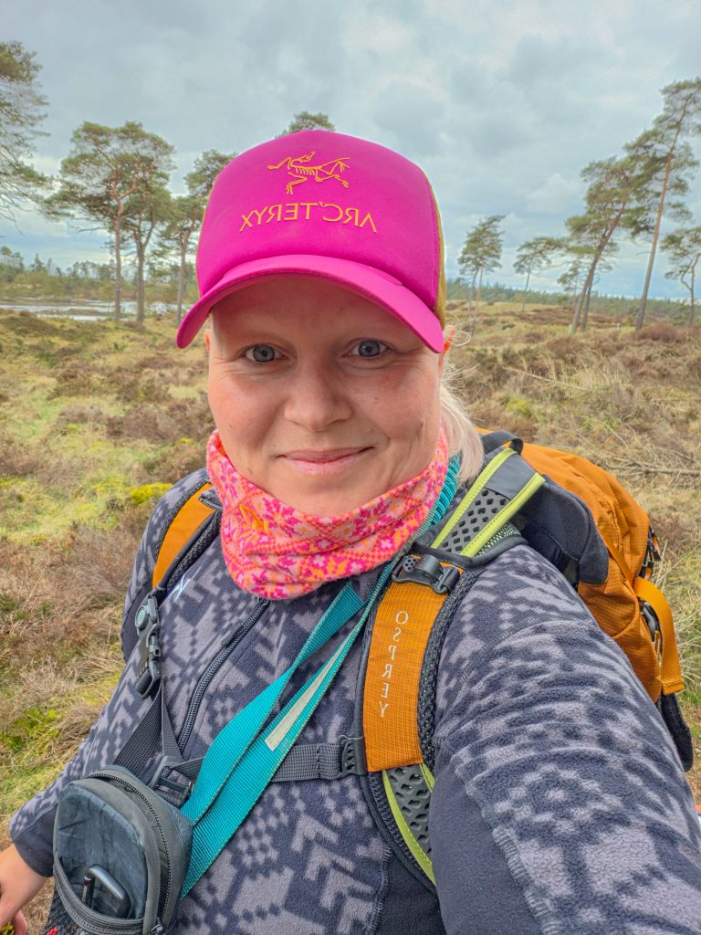 Woman hiking with a backpack through a heathland landscape in Denmark.