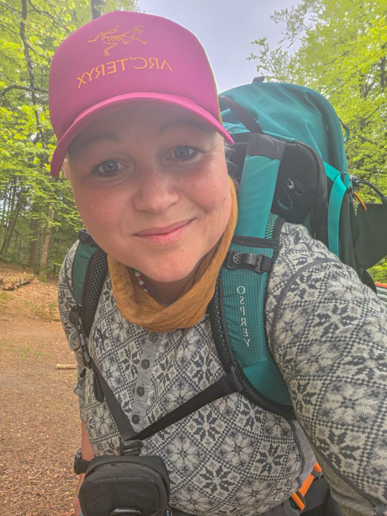 Woman hiking with a large backpack on a forest trail in Denmark.