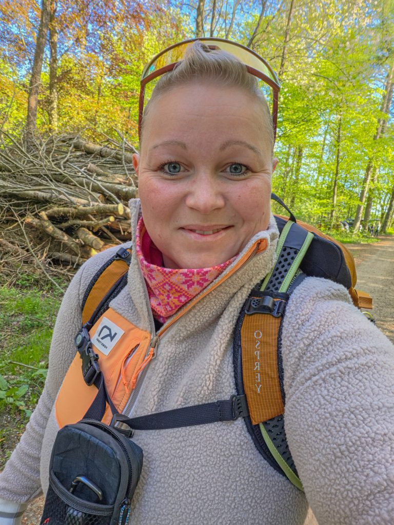 Woman wearing a fleece jacket and hiking backpack on a woodland hike.