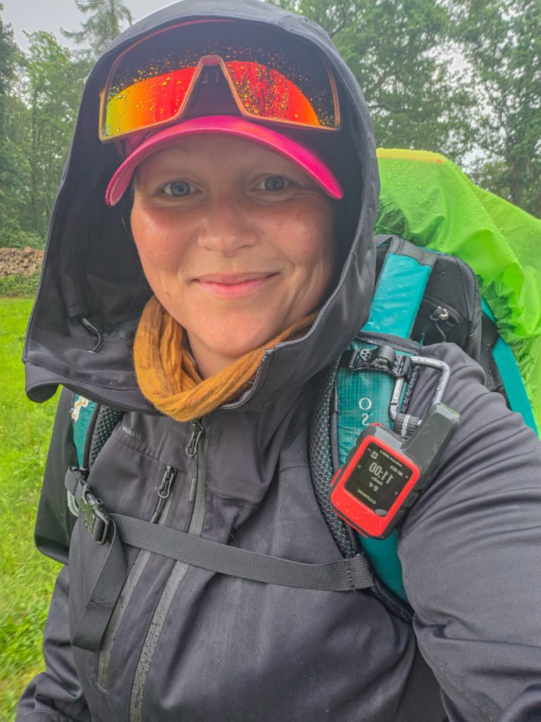 Woman hiking in the rain with a backpack and waterproof outdoor clothing in Denmark.