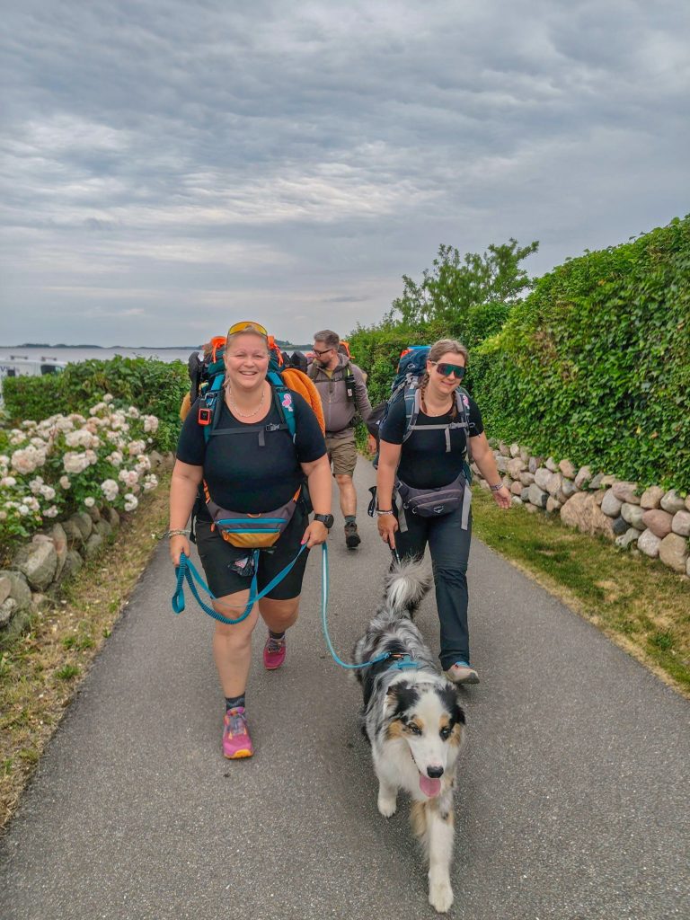 Woman hiking with friends and her Australian Shepherd on a multi-day hiking trip in Denmark.